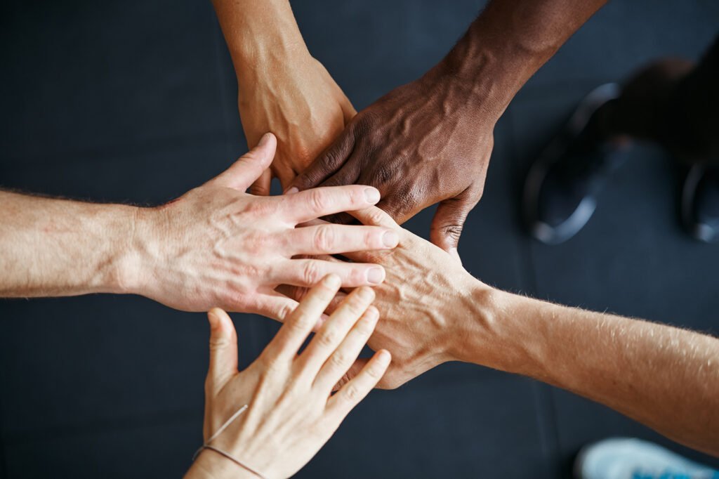 diverse people standing with their hands together